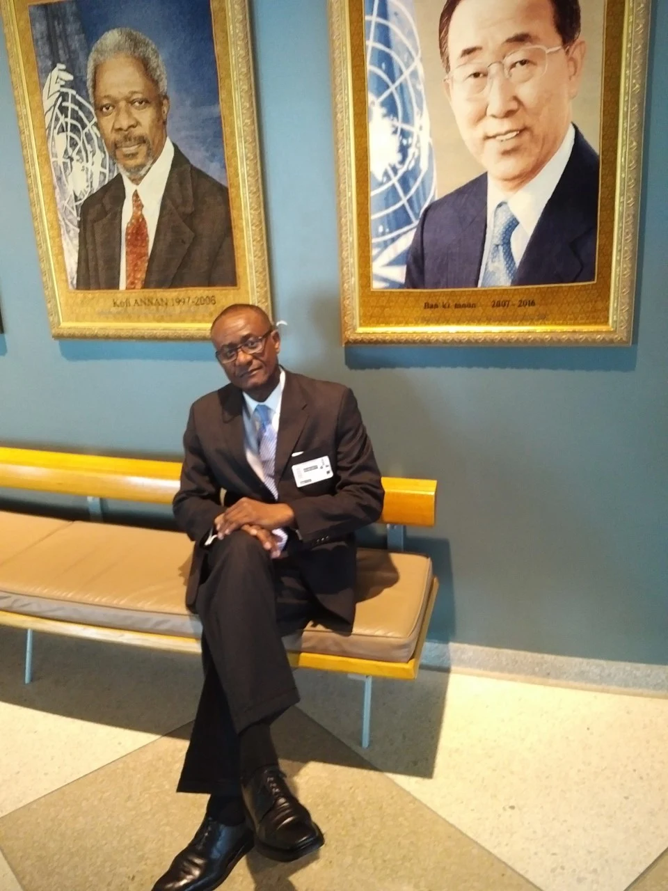 Leslie Beckett Samuel at the United Nations, seated beneath portraits of former Secretaries-General